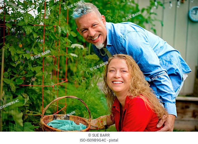 Portrait of mature gardening couple by tomato plants in garden