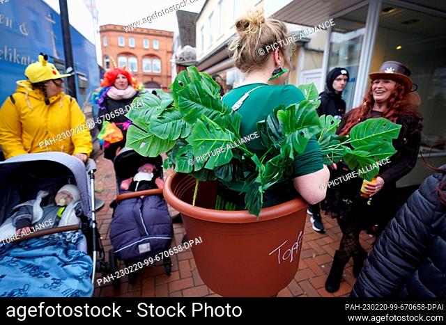 20 February 2023, Schleswig-Holstein, Marne: A woman dressed as a potted plant walks through the city center during the Rose Monday parade of the Marner...
