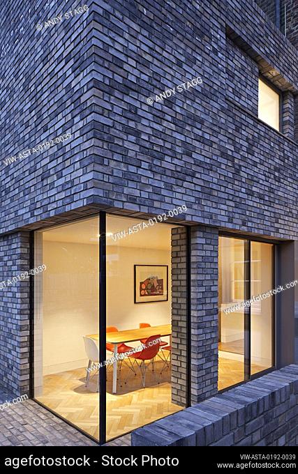 Dusk view of double-height rear extension with corner window on ground level. Queens House, London, United Kingdom. Architect: Paul Archer Design - Architects &...
