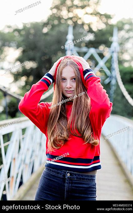 Portrait of teenage girl on a bridge, red hoodie sweater