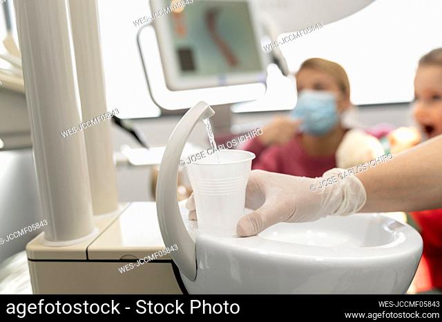Dentist filling glass of drinking water at dental clinic