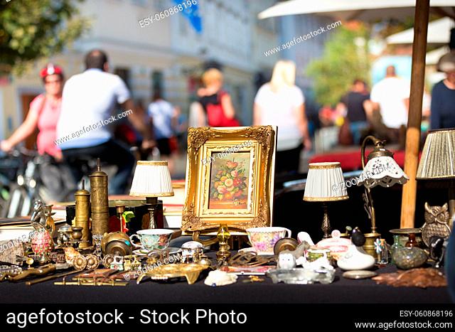 Market boot with objects beeing selled at the weekend flea market in the city center. Curious visitors in the background