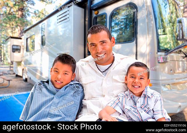 Happy Hispanic Father and Sons In Front of Their Beautiful RV At The Campground