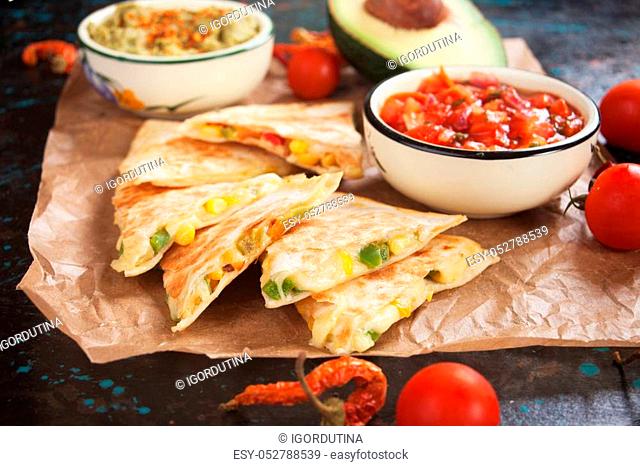 Mexican quesadillas, cheese and vegetables filled tortilla wraps with salsa and guacamole