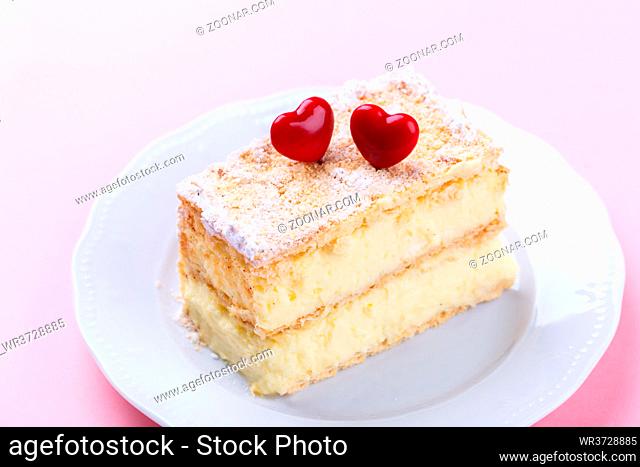 French Mille feuille cake with vanilla cream decorated with hearts on a pink background for Valentine's day