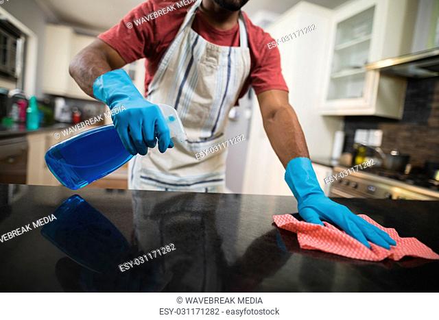 Mid section man cleaning marble counter in kitchen