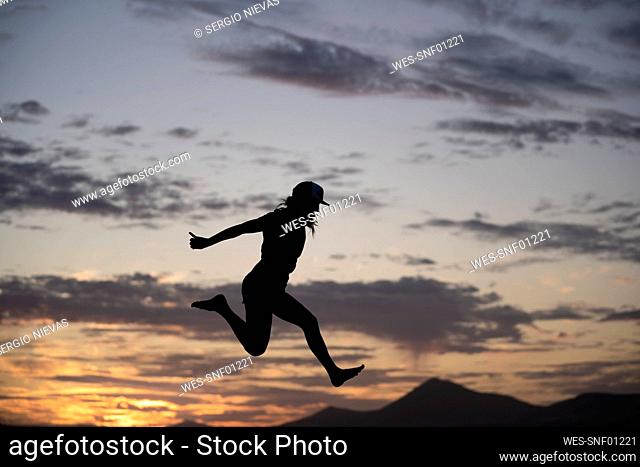 Excited woman jumping during sunset