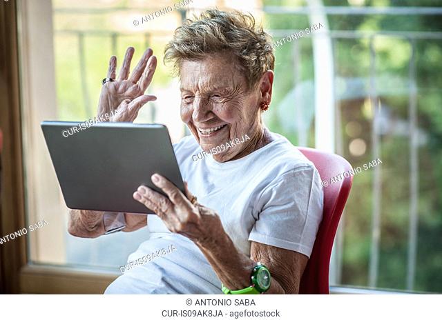 A very senior woman using digital tablet on apartment balcony