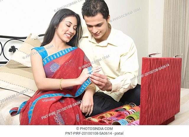 Man putting bangles on a woman's hand