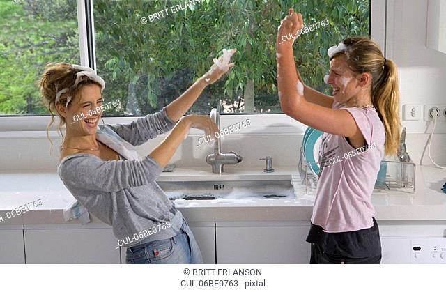 Sisters having bubble soap fight at sink