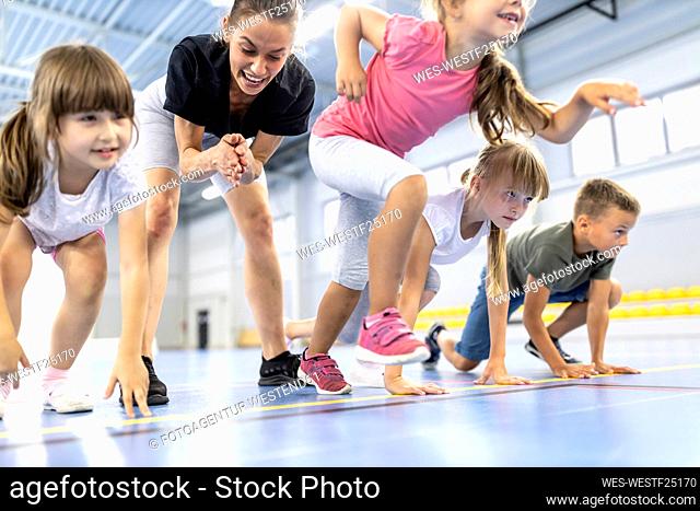 Girl starting race with friends by teacher cheering in background