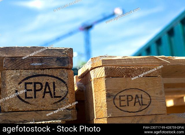 SYMBOL - 03 June 2023, Berlin: Wooden Euro pallets with the ""EPAL"" sign printed on them are stacked, while a construction crane can be seen in the background