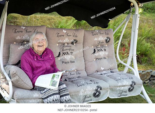 Senior woman sitting on swing bench