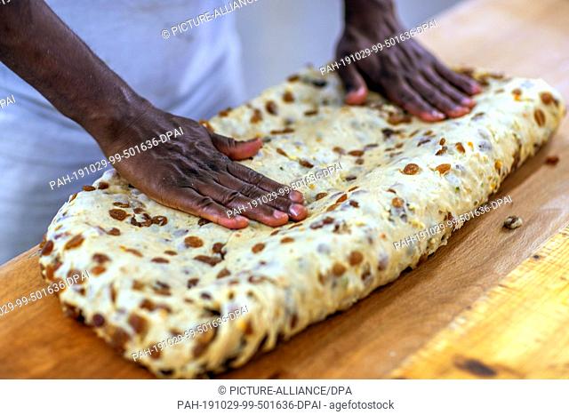 18 October 2019, Saxony, Dresden: Moussa Duale from Guinea forms raw dough into large Stollen in the Dresden bakery. The Dresden Christstollen is handmade by...