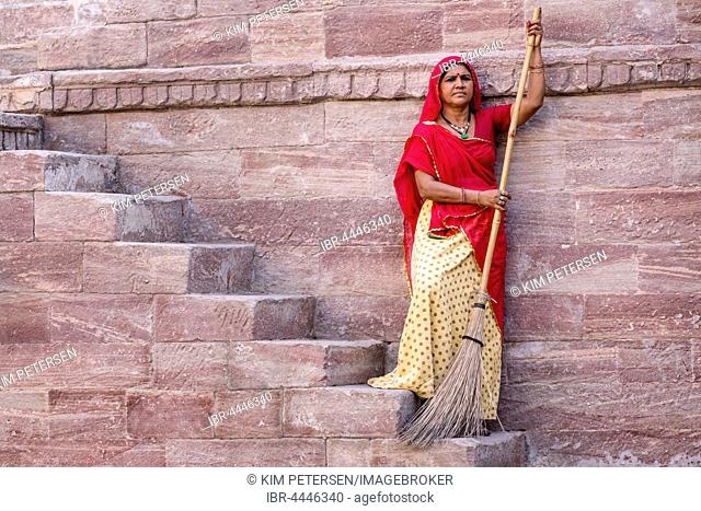 Woman in Sari sweeping steps, resting, Toorji Ka Jhalara, The Step Well, Jodphur, Rajasthan, India