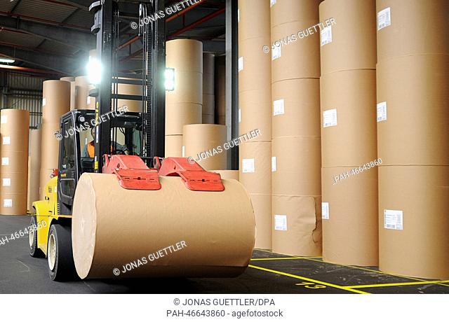 A forklift truck drives past packaged paper rolls at the logistics hall of company Stora Enso in Hagen, Germany, 20 February 2014