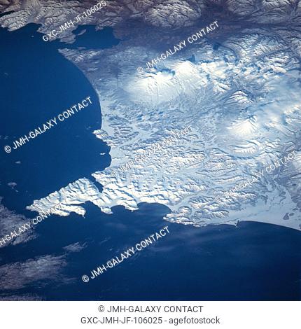 The mountainous snow-covered Shipunsk Peninsula can be seen in this southwest-looking view. The Shipunsk Peninsula's (arrowhead-shaped feature) is located on...