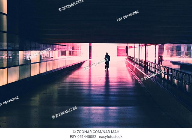 silhouette of a single person walking in  tunnel