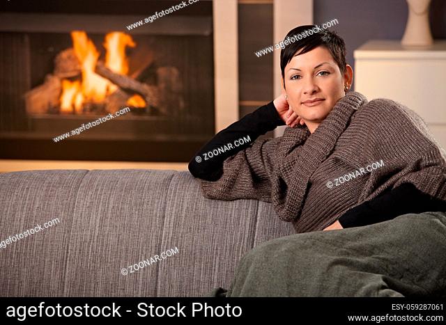 Woman sitting on sofa at home on a cold winter day, reading book