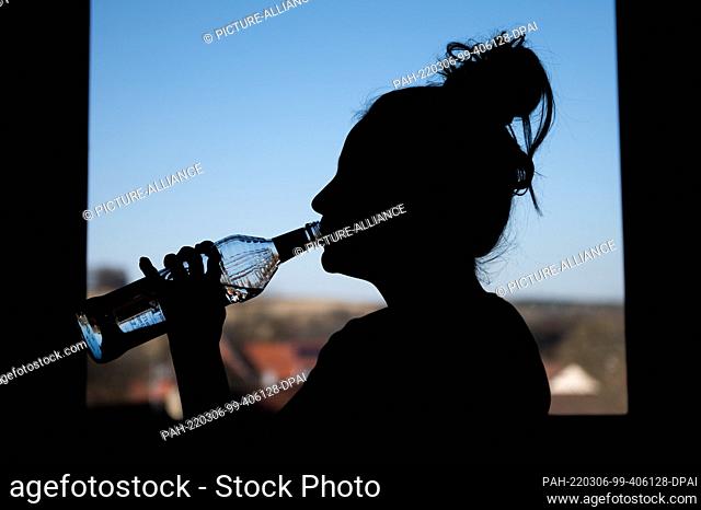 04 March 2022, Baden-Wuerttemberg, Rottweil: Illustration: A teenage girl drinks a bottle of vodka in her room (Re dpa ""DAK: Depressive kids abuse addictive...