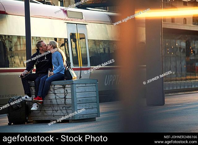 Couple kissing at train station platform