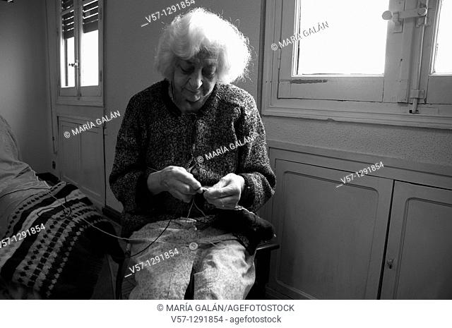 Old woman knitting at home. Black and white