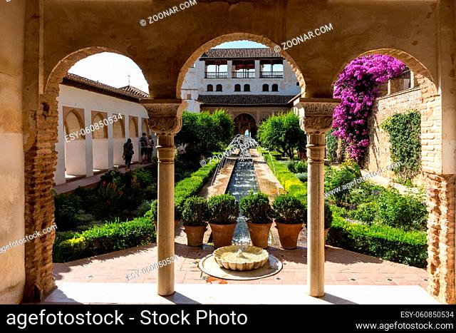 View of The Generalife courtyard, with its famous fountain and garden through an arch. Alhambra de Granada complex at Granada, Spain