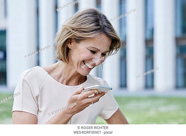Happy businesswoman using cell phone outdoors