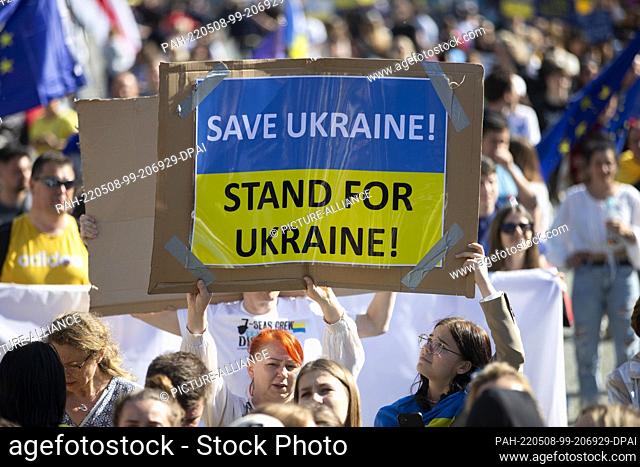 08 May 2022, North Rhine-Westphalia, Cologne: A demonstrator holds a sign reading ""Save Ukraine! Stand for Ukraine!"" during the peace demonstration...