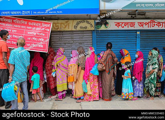 Women are waiting in a queue to buy Rice and Flour from the open market sale (OMS) dealers in Modu Shohid, Sylhet, Bangladesh.Â