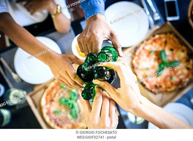 Group of friends having pizza and beer at home