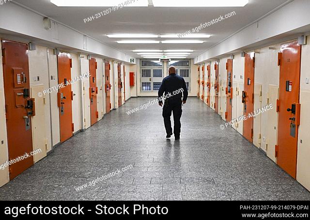 07 December 2023, Berlin: A prison officer walks past cell doors in the access department of Moabit prison during the presentation of plans for a suicide...