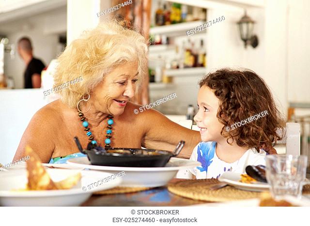 Grandmother And Granddaughter Enjoying Meal In Restaurant