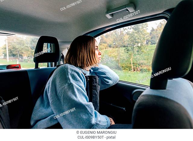 Woman looking out of window in backseat of car