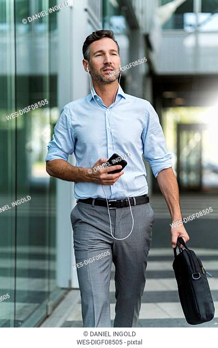 Businessman with cell phone and earphones on the go