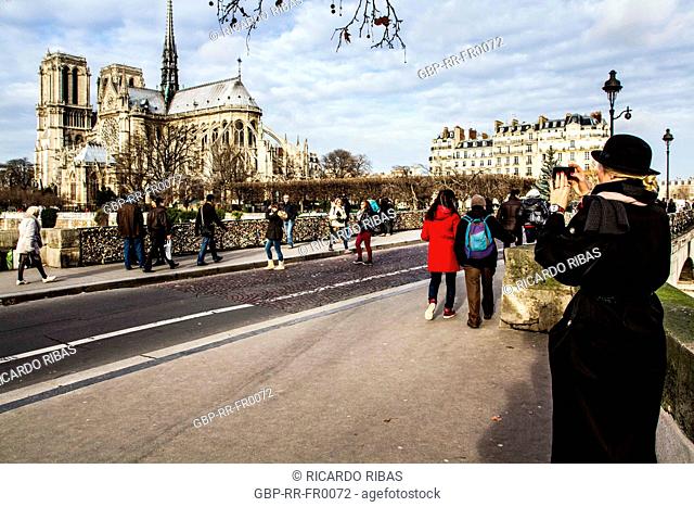 Tourists on Pont de l'Archevêché and Notre Dame Cathedral in the background. Paris, France. 02.01.13