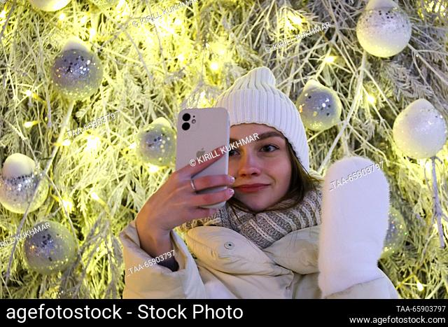 RUSSIA, NOVOSIBIRSK - DECEMBER 19, 2023: A girl takes a selfie in front of a Christmas tree in Lenina Square. Kirill Kukhmar/TASS
