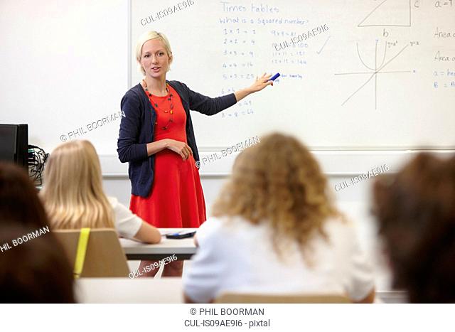 Female teacher using white board in front of class