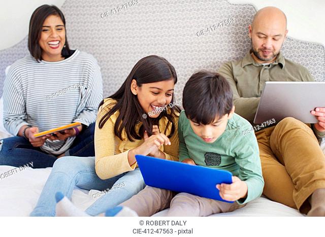 Happy family using technology on bed