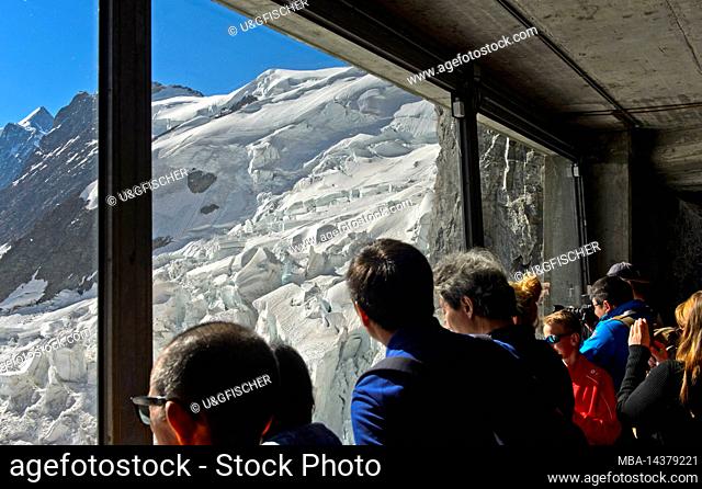 Tourists look through a glass window at the Eigerwand station of the Jungfrau Railway at the ice quarries of the Eiger glacier, Grindelwald, Bernese Oberland