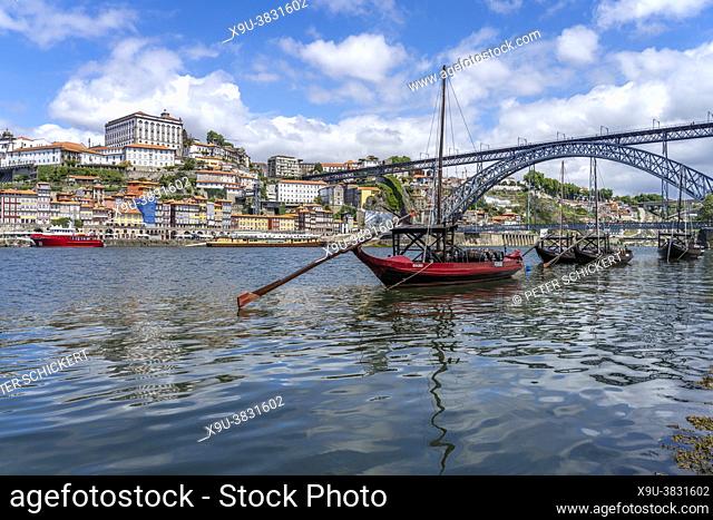 view over the traditional Portuguese wine barrel cargo boats Rabelo at the douro promenade Cais de Gaia to the old town of Porto and the Ponte Dom Luís I bridge