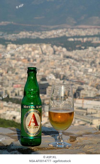 Glass and a bottle of beer on a ledge over looking the city of Athens, Greece