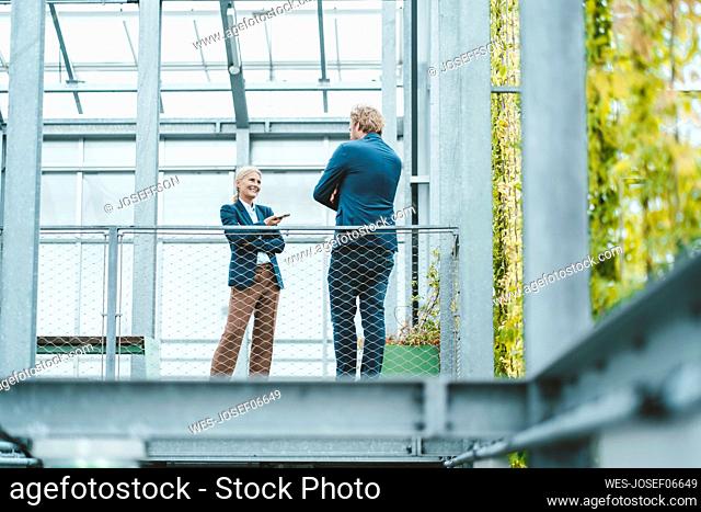 Agronomist discussing with coworker in greenhouse