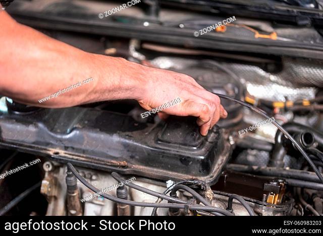 Auto mechanic working on car engine at repair service. Close up view