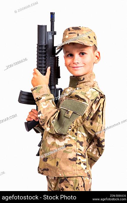 Young boy dressed like a soldier with rifle isolated on gray background