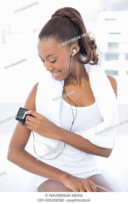 Smiling athletic woman changing music on her mp3