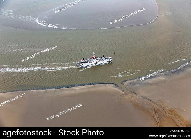 Dutch ferry boat at Wadden Sea navigating with low tide through small channels between sandbanks