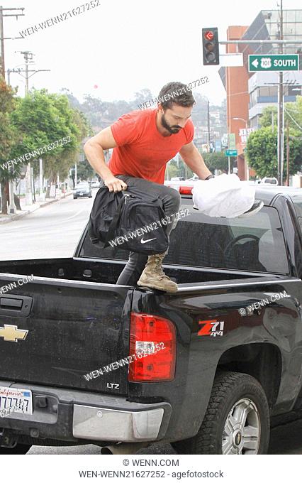 A bearded Shia LaBeouf wearing his favourite old red 'Mighty Alpha Superstars 1981-1982' t-shirt jumps down from the back of a pickup truck carrying a Nike...