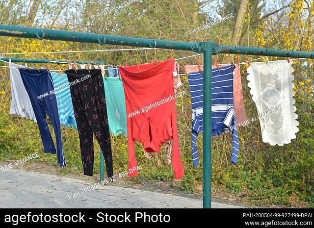 09 April 2020, Saxony, Leipzig: Freshly laundered laundry is hanging on a clothesline in a laundry drying area directly next to a residential building in...
