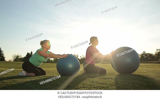 Adult women working out in park with fitness balls